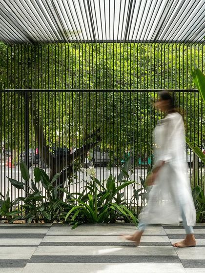 The entrance to the Soul Spring center is a transitional zone designed to slow the pace and connect visitors with nature. The slatted pergola creates a beautiful play of light and shadow, while the glass doors reflect the surrounding greenery.