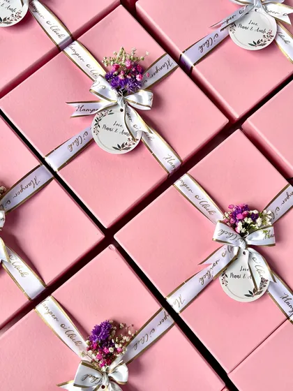 A top-down view of my pink baby shower return favor boxes, all beautifully tied with a custom ribbon and a delicate floral bunch.