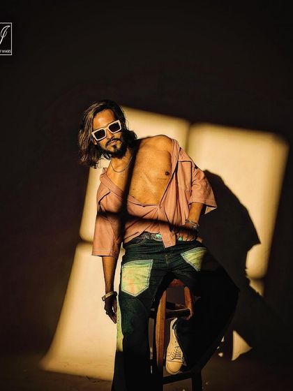 A confident and relaxed pose from the same high-fashion series. The combination of an open shirt, stylish sunglasses, and dramatic lighting creates a memorable and aspirational image.