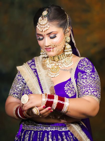 The bride adjusting her bangles, a candid-style shot that highlights the complete look, including the traditional chooda.