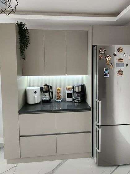 A wider view of the pantry and coffee station, showing its seamless integration next to the refrigerator. The consistent design language creates a cohesive and organized look in the kitchen area.
