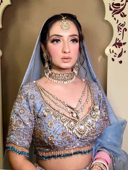 The side profile highlights the heavy earrings and the way the dupatta is draped to complement the layered necklaces.