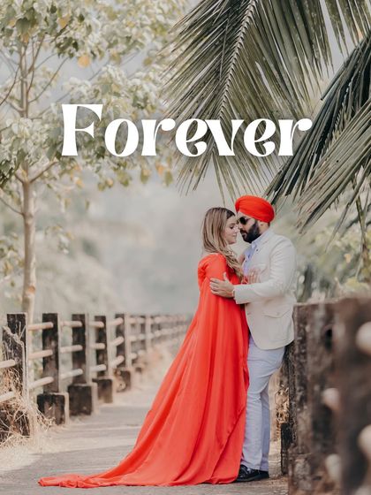 "Forever." An intimate embrace on a bridge surrounded by lush greenery. The vibrant red of her turban and the flowing fabric of her dress create a stunning visual.