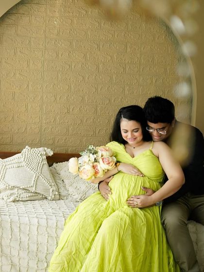 A quiet moment on our studio bed set, showing the couple's connection as they look down at the baby bump.
