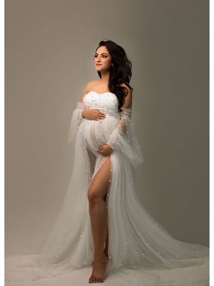 A solo portrait capturing the quiet strength and beauty of motherhood. The flowing white gown adds a touch of ethereal grace to this timeless image.