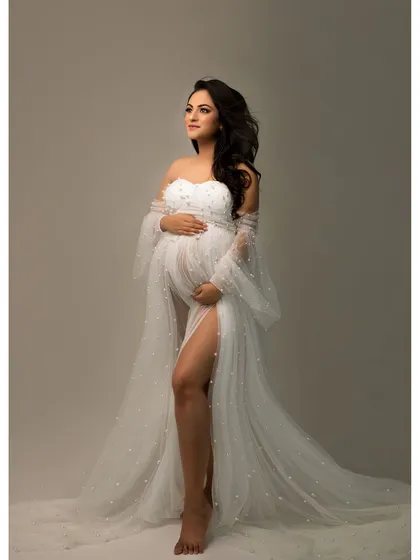 A solo portrait capturing the quiet strength and beauty of motherhood. The flowing white gown adds a touch of ethereal grace to this timeless image.