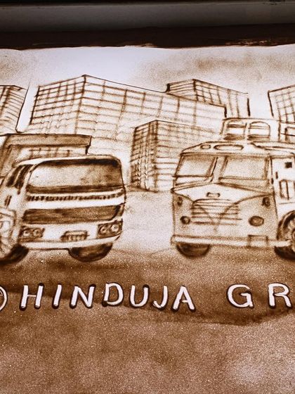 A completed sand art frame for the Hinduja Group's Ashok Leyland, showing their vehicles against a city skyline. This was part of a larger video project.