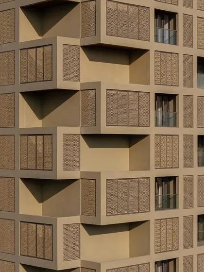 A detail of the facade shows the intricate pattern of the stone screens and the deep, shaded balconies that provide private outdoor space for residents.