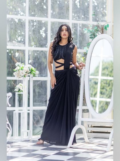 This black draped saree with a cutout waist is a bold and modern choice for a cocktail party or reception.