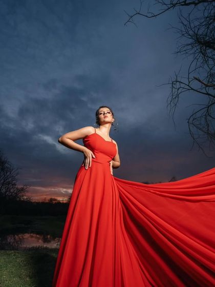 A striking silhouette against the evening sky. This red trail gown is a showstopper, perfect for creating unforgettable pre-wedding images.