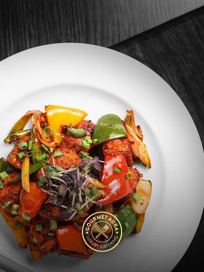 A vibrant dish of chili paneer, with colorful bell peppers and spring onions, plated on a clean white dish. This selective color photo highlights the freshness of the ingredients.