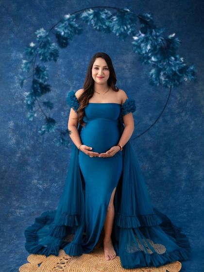 Framed by a dramatic floral hoop, this portrait is a work of art. The deep blue tones of the gown, backdrop, and floral arrangement create a cohesive and visually stunning image.