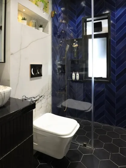 We love mixing materials for a dynamic look. This bathroom features bold blue herringbone tiles in the shower, contrasted with a white marble wall and hexagonal floor tiles for a truly unique design.