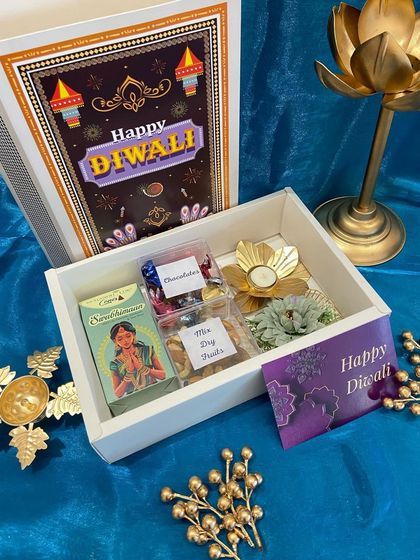 A classic white box with a festive Diwali-themed sleeve. Inside, we've packed a mix of chocolates, dry fruits, and a beautiful lotus candle holder for a complete festive feel.