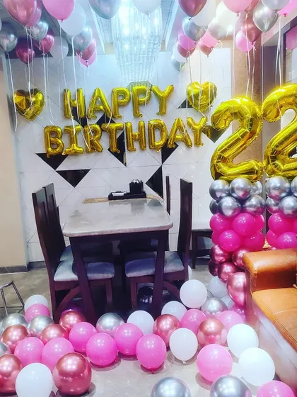 A fun and girly 22nd birthday home decoration. The room is filled with pink, silver, and white balloons, with large foil balloons for the age.