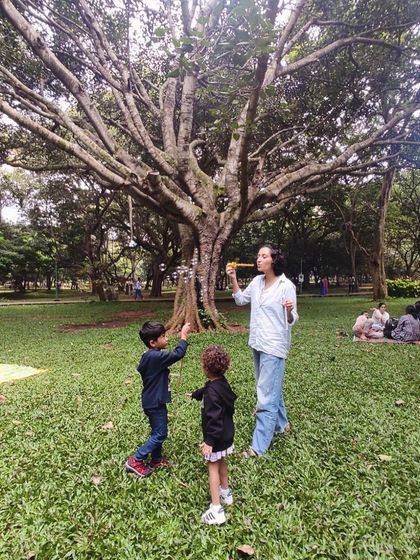 A mother helps her children create bubbles, a simple activity that brings so much delight. We believe in the magic of simple, sensory play.