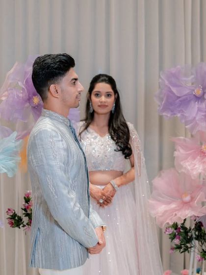 A sweet portrait of the couple at their Roka ceremony. The backdrop of giant, whimsical paper flowers in pastel shades creates a fun and dreamy setting.