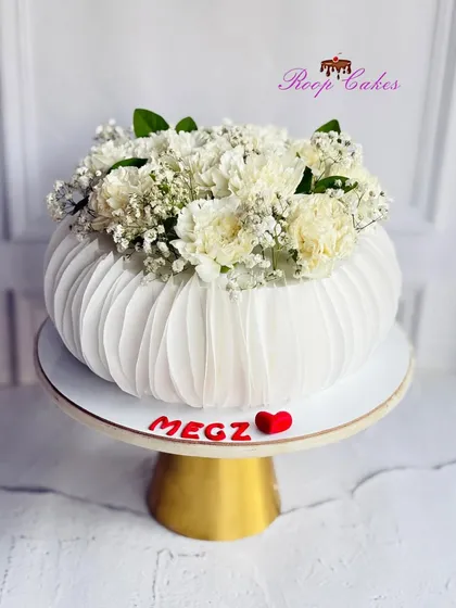 This cake is designed to look like a modern flower vase, with delicate, edible wafer paper creating a pleated texture. It's topped with fresh baby's breath, blending the line between cake art and floral design for a truly elegant celebration.