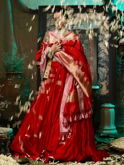 An artistic shot with falling petals for Soho Begum, adding a layer of movement and magic to this vibrant red ensemble.