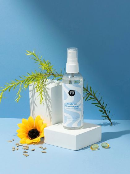 A fresh, nature-inspired composition. We styled this hair refresh spray with a sunflower and botanical elements against a sky-blue background to communicate its natural ingredients and light, airy feel.