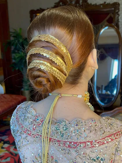 This golden wrapped bun is one of my signature creations for the bride who wants a truly unique and traditional look. The intricate wrapping detail adds a touch of royal elegance, making it a memorable wedding day hairstyle.