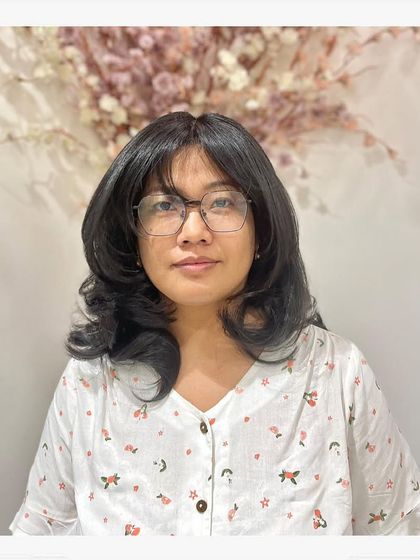 A client with a fresh layered haircut and soft styling. The cut includes a gentle fringe and face-framing pieces, creating a soft and flattering look.