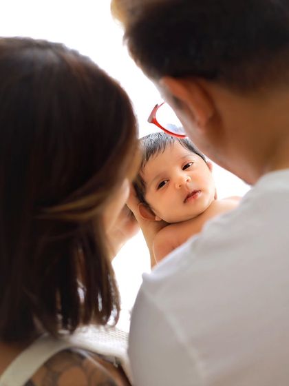 An over-the-shoulder perspective showing the parents' view as they look down at their newborn. This intimate angle makes the viewer feel like they are part of the moment.