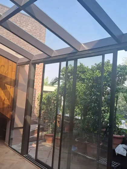 This angle shows how our glass extension integrates with the home's interior, featuring wood-paneled walls and a seamless transition. The transparent roof and walls make the space feel expansive and bright.