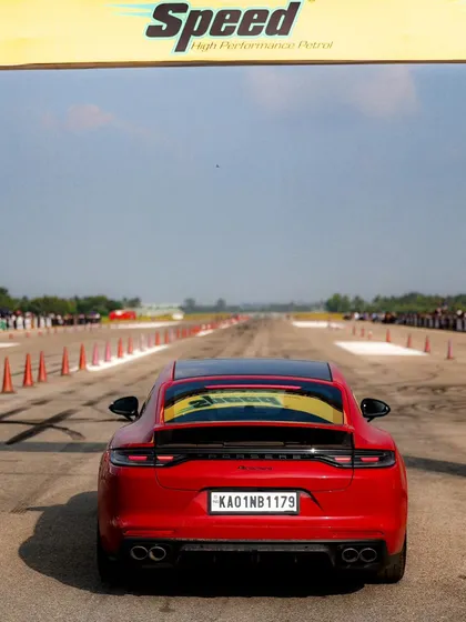 A red Porsche Panamera at the starting line, with the "Speed" branding arch in the background. This is a great example of a luxury performance sedan taking on the drag strip.
