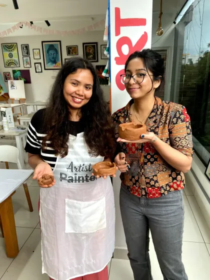 Two friends proudly display the small clay pots they made. It's a great way to spend time together and learn a new skill.