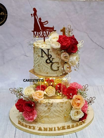 A luxurious 5kg chocolate anniversary cake with a hexagon light-up spacer. The two tiers are decorated with an engraved pattern, real roses, and a custom initial topper.