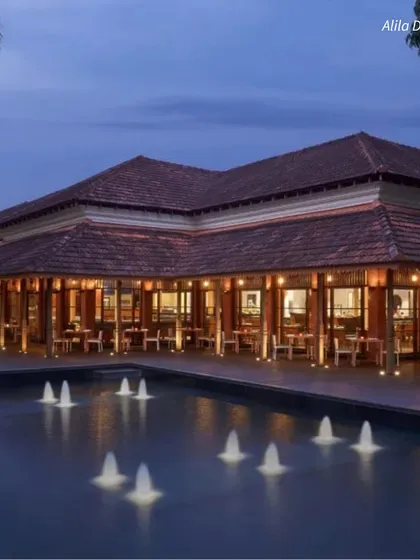 The elegant poolside of Alila Diwa, Goa, at dusk. The warm lighting and tranquil water create a romantic and sophisticated ambiance.