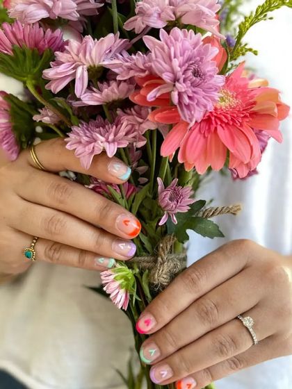 A beautiful shot of the Valentine's nails with a bouquet of flowers. The colors are so vibrant and happy.