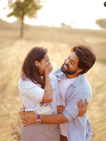 A playful and candid moment between a couple in a sun-drenched field. Capturing your genuine laughter is what makes a photoshoot feel personal and real.