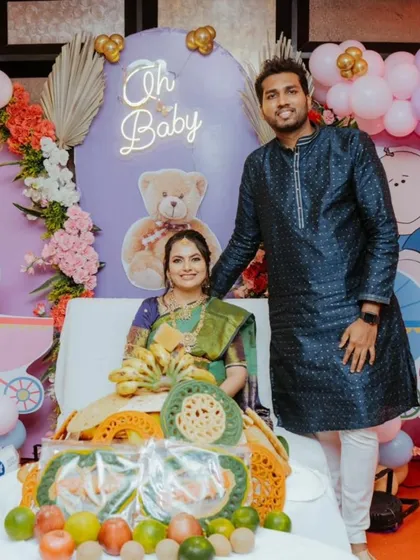 A lovely picture of the couple at their baby shower. The mom-to-be is wearing a complete set of traditional gold-finish jewellery that perfectly complements her green saree.