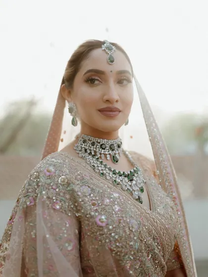 A close-up portrait of the bride, her face softly lit and her expression serene. The focus on her beautiful features and stunning diamond and emerald jewelry highlights her bridal glow.