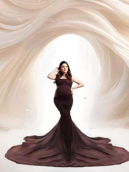 This portrait showcases a beautiful brown gown against a creative, cave-like fabric backdrop. The pose and lighting create a high-fashion, editorial feel.