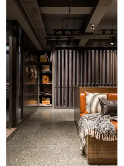 The warm leather of the seating bench provides a rich contrast to the cool concrete floor and dark grey walls.