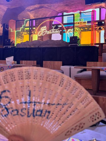 A guest's view of the DJ stage, with a custom branded fan in the foreground, showing how even small details contribute to the event's theme.