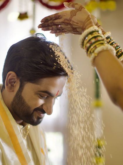 The Akshataropana ritual in a Kannada wedding, where the couple showers each other with blessed rice. This action shot captures the movement and significance of the tradition, symbolizing blessings, prosperity, and happiness.