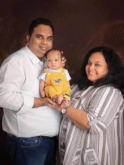 A beautiful family of three. This classic portrait captures the joy and pride of new parents as they hold their baby boy together.