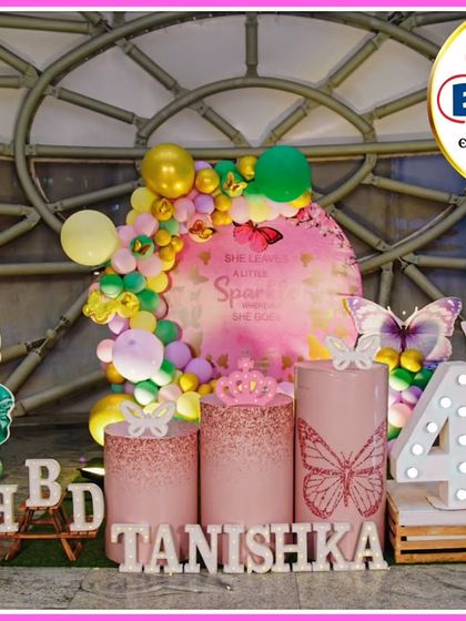 A princess and butterfly-themed fourth birthday. The pink and yellow decor features Ariel and fairy cutouts, a 'She leaves a little sparkle' backdrop, and a large light-up number '4'.