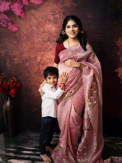 A mother and her son share a hug in this beautiful, regal maternity portrait. The rich, dark backdrop and her elegant pink saree create a striking and emotional image.