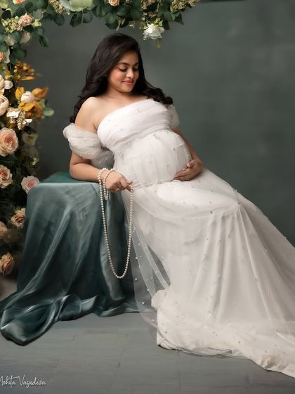 Seated like a queen on her throne. This pose, surrounded by flowers, creates a regal and romantic portrait, celebrating the goddess you are.