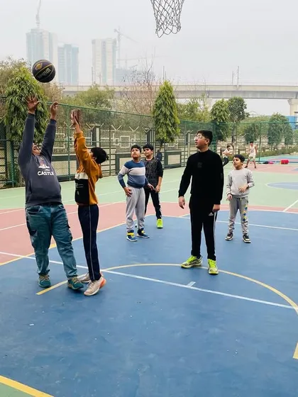 A coach demonstrates proper shooting form to a young player.