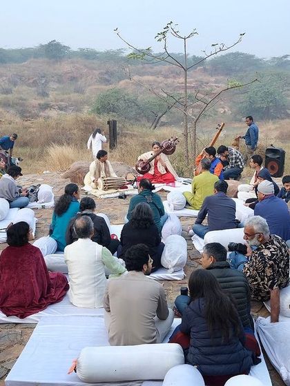 The audience, seated on mats, listens to the mesmerizing sounds of the Rudra Veena as the sun rises over the Aravalis.