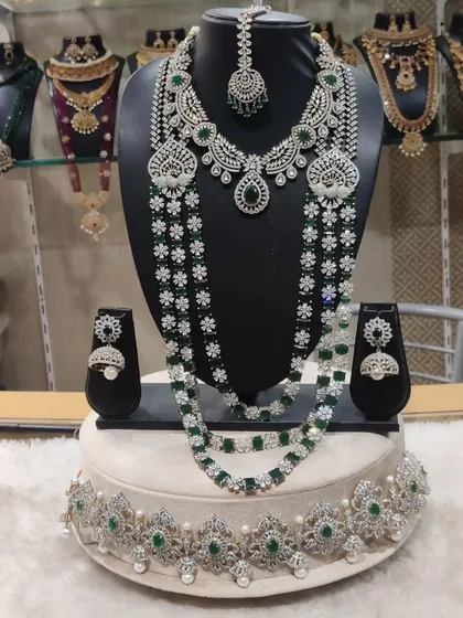 A perfect choice for a modern reception look, this diamond and emerald look-alike set offers breathtaking sparkle. It includes a layered haram, a matching choker, earrings, and a maang tikka, all designed to make a statement.