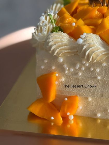 A corner detail of the Mango Maharaja cake, showing the fresh mango pieces and delicate pearl sprinkles.