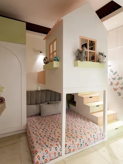 I love finding clever ways to use space. For this room, I designed a custom house-shaped bunk bed with built-in stairs that double as storage drawers. The soft pastel colors and cozy lower bunk create a perfect little haven for sleep and play.