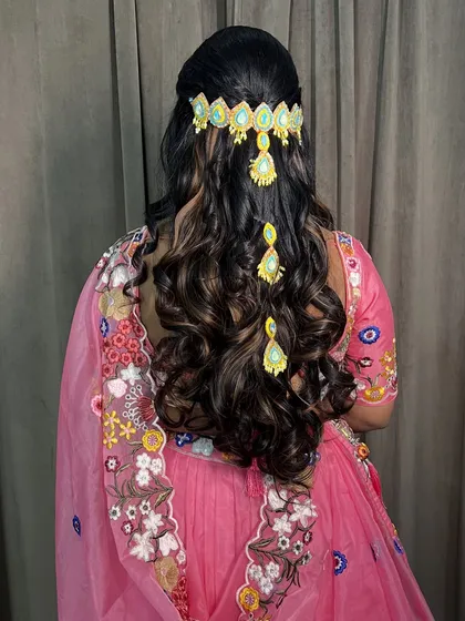 A modern Haldi hairstyle with open curls and a statement hair accessory, perfect for a lehenga.